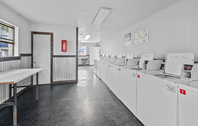 a laundry room with white walls and a black tiled floor