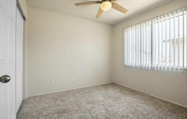 Bedroom with sliding closet door at the left, ceiling fan, carpeted flooring