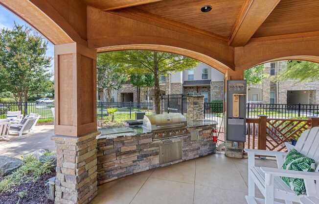A patio with a stone wall and a grill.