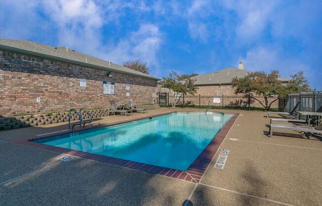 A large outdoor swimming pool surrounded by a brick wall.