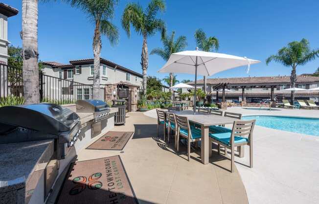an outdoor grill area with a table and chairs