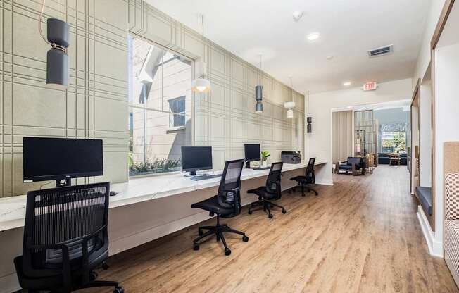 A modern office with wood floors and black chairs.