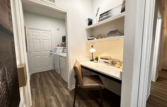 a home office with a desk and a door to a kitchen