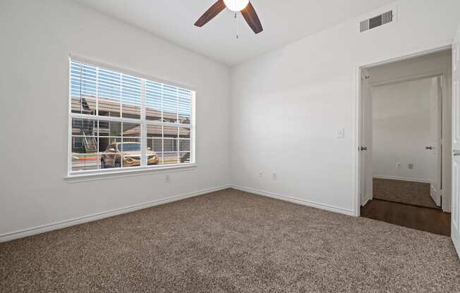 A room with a ceiling fan and a window with blinds.