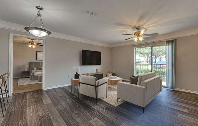 A living room with a grey couch and a television on the wall.
