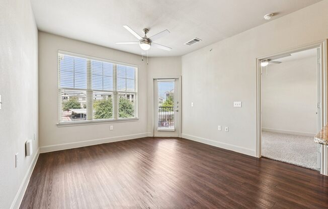 A room with a ceiling fan and a view of the outside through the window.