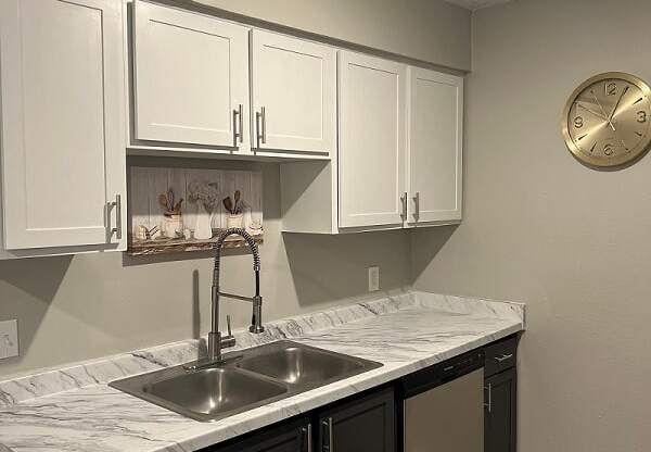 a kitchen with white cabinets and a clock on the wall