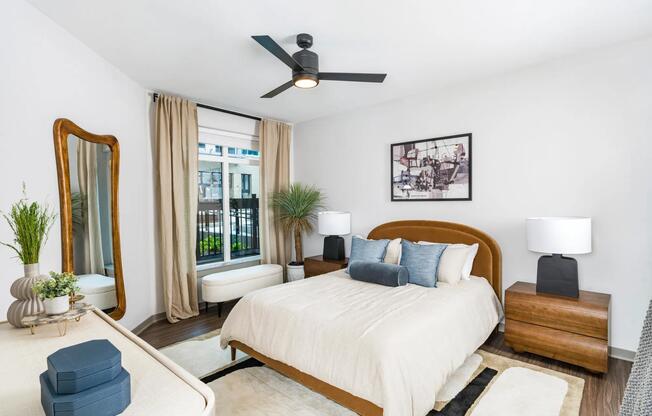 Modern ceiling fan and large windows add style and function to this bedroom. Wood-style flooring and neutral wall tones complete the upscale finish.