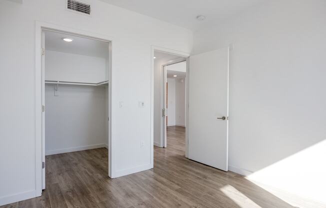 a bedroom with white walls and a door to a closet