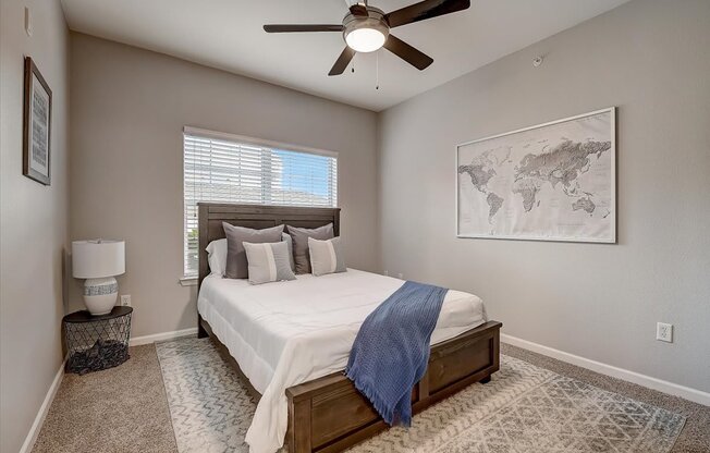 a bedroom with a ceiling fan and a large window