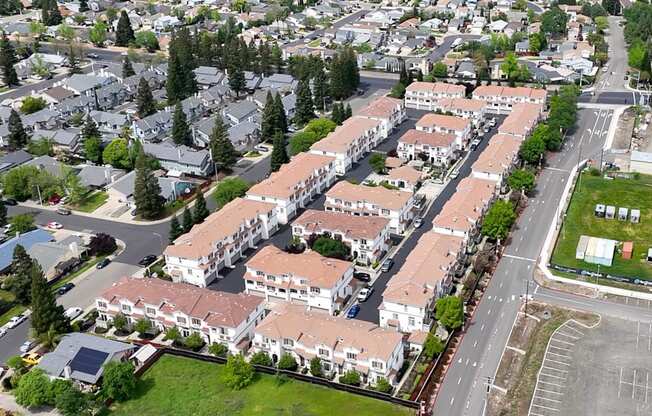 A large apartment complex is surrounded by smaller buildings and trees.