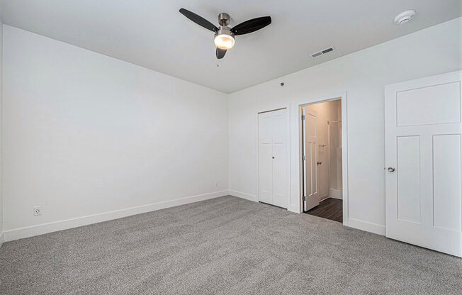 an empty living room with a ceiling fan