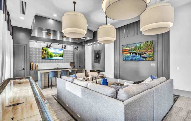 A modern living room with a grey couch and a pool table.