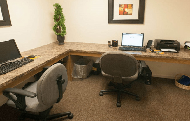 a desk with two chairs and a laptop computer