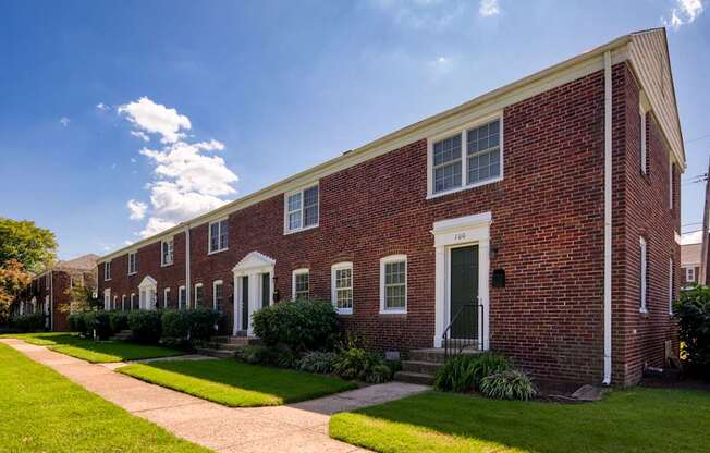 A row of red brick houses with green lawns in front.