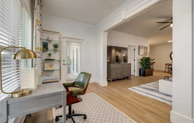 A room with a desk, chair, and a lamp.