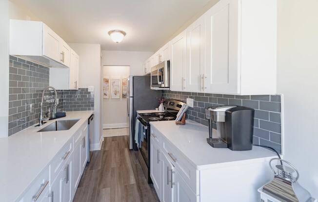 a kitchen with white cabinets and stainless steel appliances and a sink