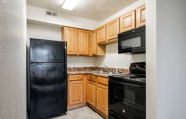 A kitchen with black appliances and wooden cabinets.