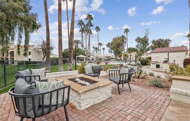 A patio with a fire pit and chairs.