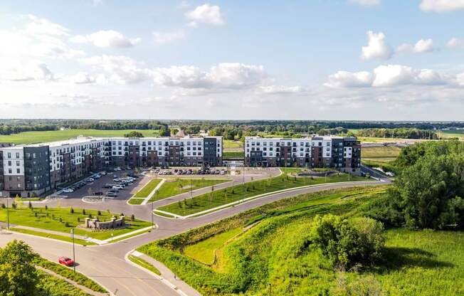 A large, modern building complex with a parking lot in front.