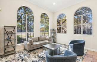 a living room with couches and chairs and windows