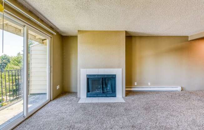 an empty living room with a fireplace and a sliding glass door