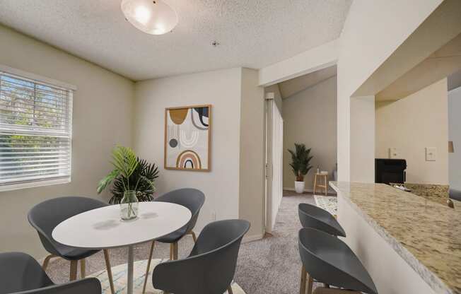 a dining area with a table and chairs and a kitchen with a counter and a