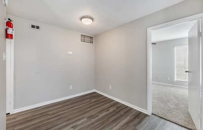 the living room of an apartment with wood flooring and a door to the bedroom