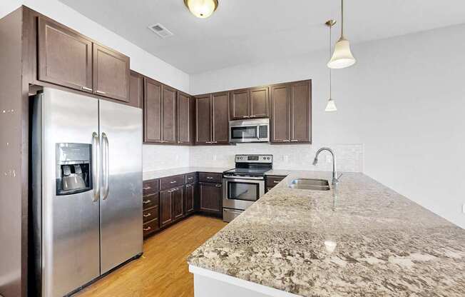 A kitchen with a granite counter top and stainless steel appliances.