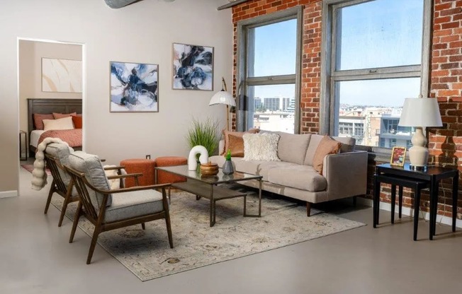 a living room with a couch and chairs and a brick wall