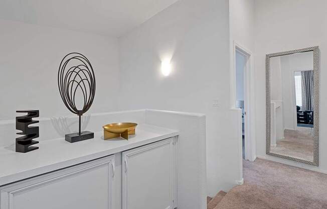 A white bathroom with a mirror and a black sculpture on the counter.