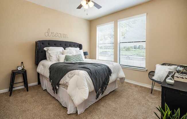 A bedroom with a bed, a desk, and a ceiling fan.
