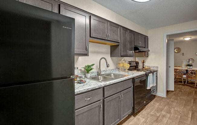 Kitchen, wood-like flooring, granite countertops, black appliances, extended sink