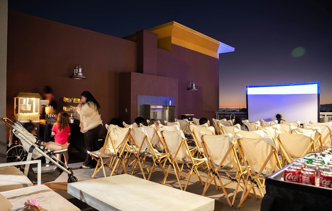 A movie theater with people sitting in the chairs and a screen in the background.