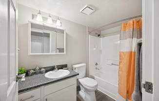 A bathroom with a white toilet, sink, and mirror.