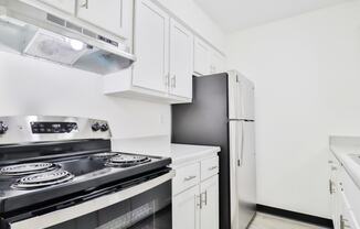 a kitchen with white cabinets and black appliances and a refrigerator