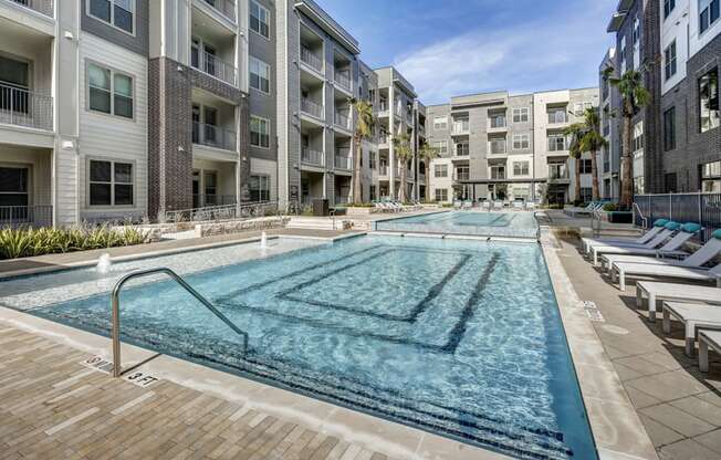an apartment pool with lounge chairs in front of an apartment building at Arise Riverside, Texas, 78741
