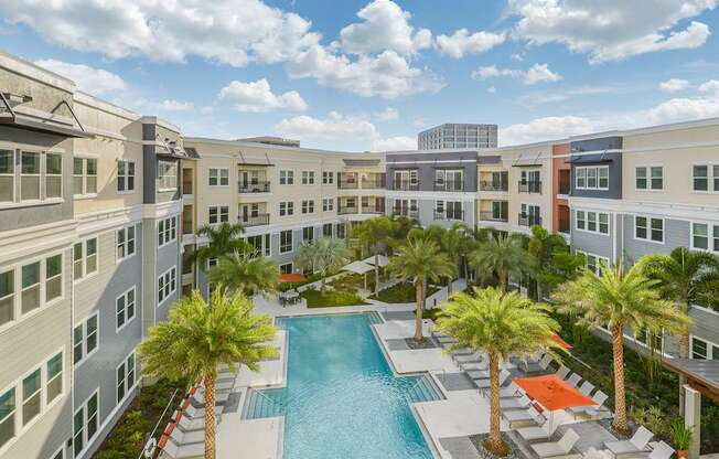 A pool surrounded by palm trees and buildings.