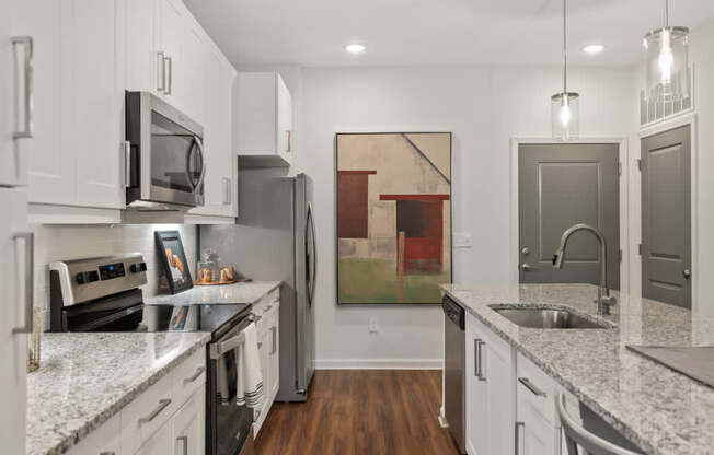 A kitchen with white cabinets and a painting hanging on the wall.