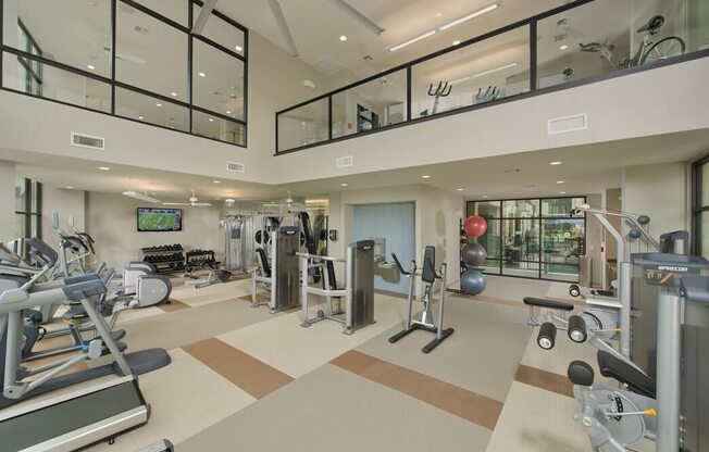 a gym with weights and cardio equipment and a window