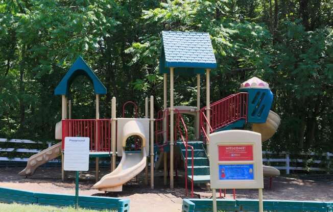A playground with a slide, a treehouse, and a sign that says "Welcome".