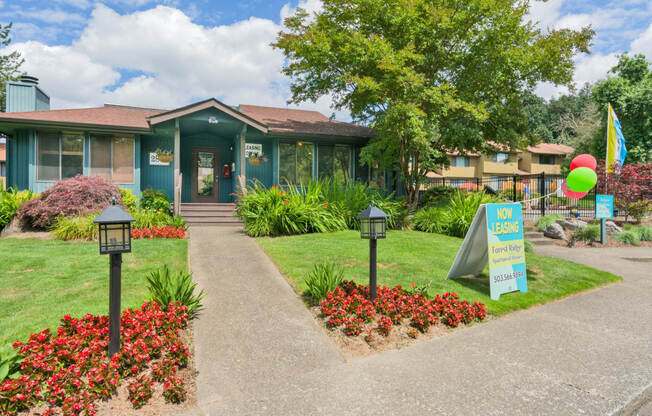 the front of a green building with a yard and a sign in front of it