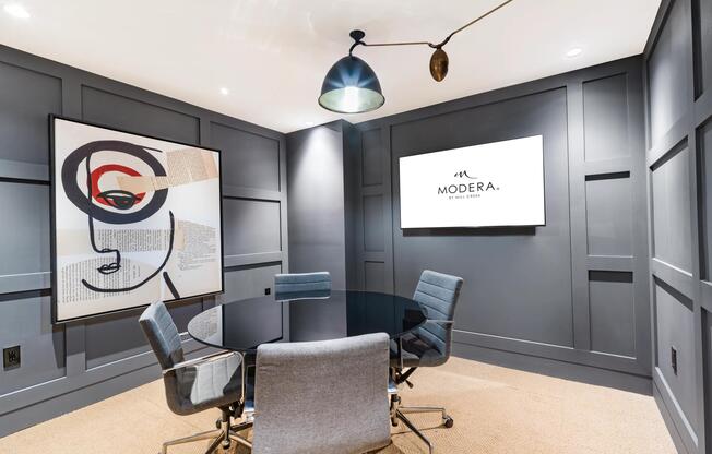 A private conference room at Modera Aventura, designed for focused meetings with tailored millwork, statement lighting, and integrated presentation technology.
