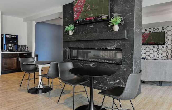 A black table with four chairs in front of a fireplace.