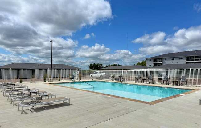 A pool with sun loungers and a building in the background.
