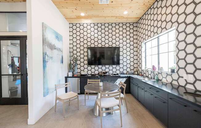 A kitchen with a black and white patterned backsplash and wooden ceiling.