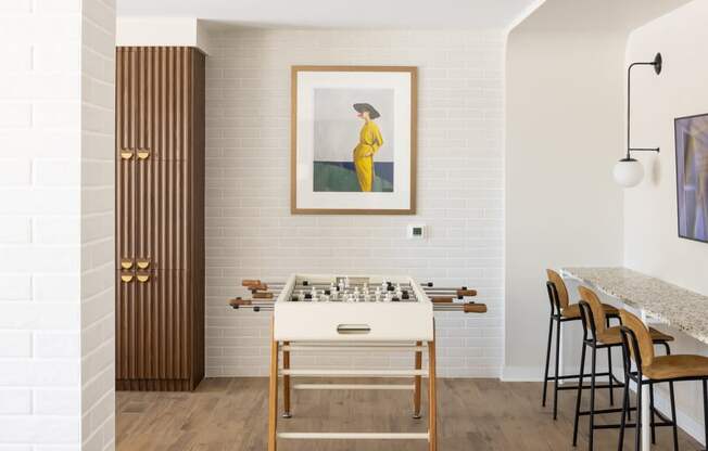 a room with a foosball table and a painting on the wall