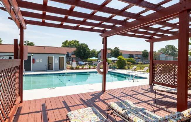 a swimming pool with a wooden deck with chairs