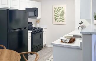 a kitchen with a black refrigerator freezer next to a stove top oven