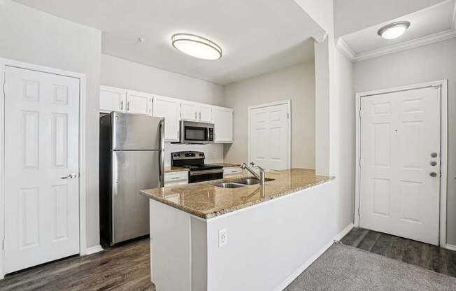 A kitchen with white cabinets and a granite countertop.
